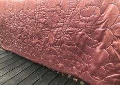 a pink quilted bedspread on top of a wooden floor