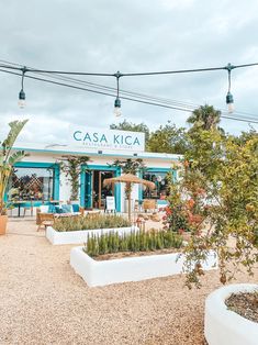 a blue and white building with plants in the foreground on a cloudy day at casa kica