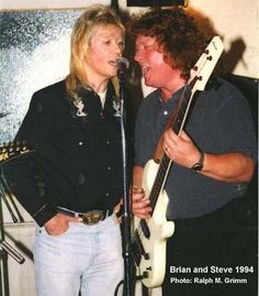 a man and woman singing into microphones while holding guitars