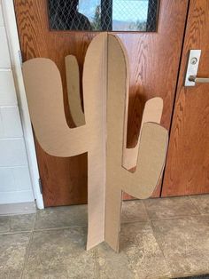 a cardboard cactus sitting in front of a door with the letter h on it's side