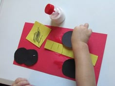 a child is making a paper car with construction paper and glue on the table top