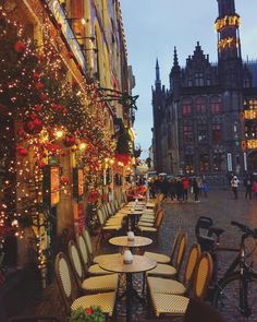 tables and chairs are lined up along the street with christmas lights strung all around them