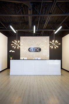 an empty reception area with lights on the ceiling and wood flooring in front of it