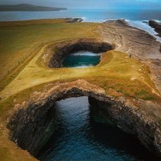 an aerial view of the ocean and land with a bridge over it that leads to a body of water