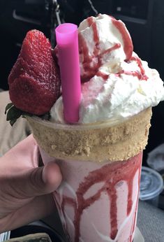 someone holding up a strawberry shortcake ice cream sundae with whipped cream and strawberries on top