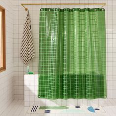 a green shower curtain in a white tiled bathroom