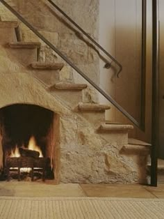 a fire place sitting inside of a stone building next to a stair case and door