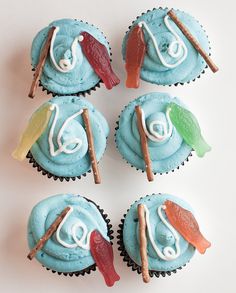 four cupcakes decorated with blue frosting and colorful decorations