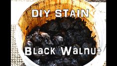 a wooden bowl filled with black walnuts on top of a table next to a cloth