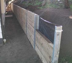 a wooden fence with a black tarp over it and some dirt on the ground