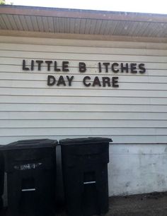 two black trash cans sitting in front of a white building that says little b itches day care