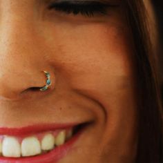 a close up of a person with a nose ring on their left side, smiling