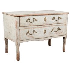 an old white dresser with two drawers on one side and gold knobs on the other