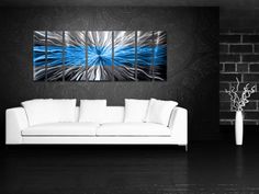 a living room with a white couch and blue wall art on the wall above it