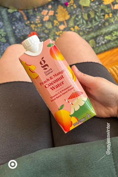 a person holding a bottle of sunscreen in their hand while sitting on a couch