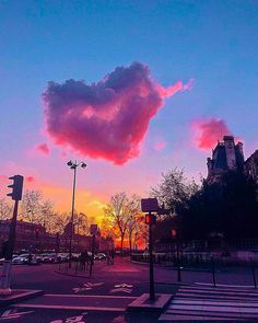 a pink cloud is in the sky over a city street