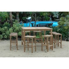 a wooden table and four chairs in front of a blue swimming pool with palm trees