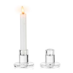 a white candle is lit in front of a glass holder with two clear candles on it