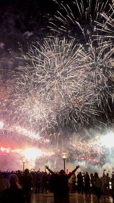 fireworks are lit up in the night sky with people standing around and looking at them