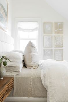 a bed with white linens and pillows in a small room next to a window