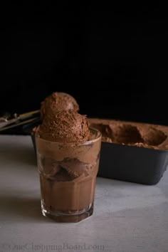 a glass filled with chocolate ice cream next to a baking pan