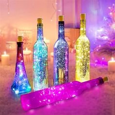 several bottles with lights in them sitting on a table next to candles and other decorations