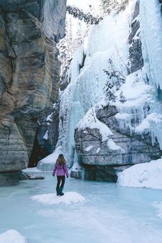 a woman standing in front of a frozen waterfall