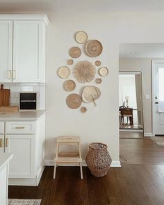 a white kitchen with lots of plates on the wall and a wooden chair in front of it