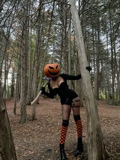 a woman dressed up as a witch in the woods with a pumpkin on her head