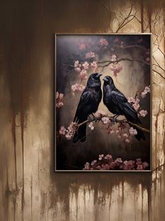 two black birds sitting on a branch with pink flowers in front of a brown wall