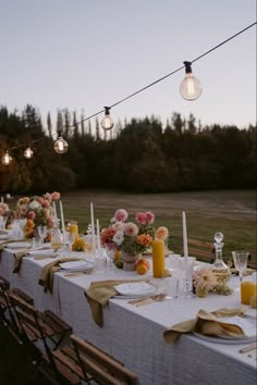 an outdoor dinner table set with candles, flowers and napkins for guests to eat