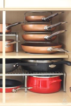 pots and pans are stacked on shelves in a kitchen cabinet with metal racking