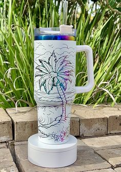 a white cup with a palm tree painted on it