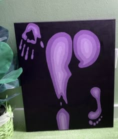 a purple painting on a black background next to a potted plant