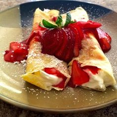 two crepes with strawberries are on a plate