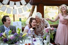 a group of people sitting around a table with flowers and candles in front of them