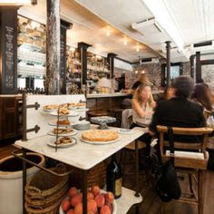 people sitting at tables in a restaurant with pies on the table and other food