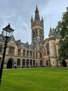 an old building with a clock tower on the top and green grass in front of it