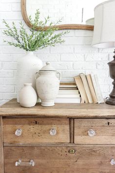 a white vase sitting on top of a wooden dresser