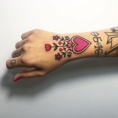 a woman's arm with tattoos on it, and a pink flowered heart