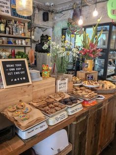 a bakery with lots of pastries on display in front of the counter and flowers