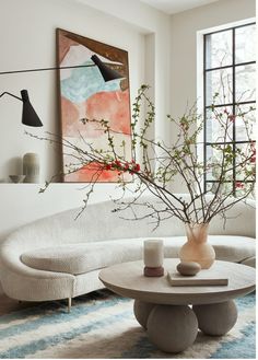 a living room with a couch, table and vase on the coffee table in front of it