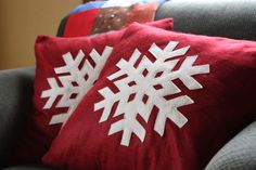 two red and white snowflake pillows on a couch