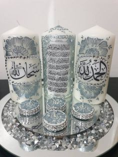 three candles with arabic writing on them sitting on top of a plate covered in crystals