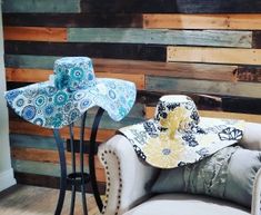 two hats are sitting on a chair in front of a wood paneled wall with an iron stand