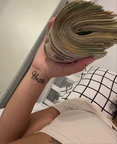 a woman with a tattoo on her arm is holding money in front of her face