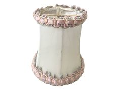 a white vase with pink trimmings on the top and bottom, sitting against a white background