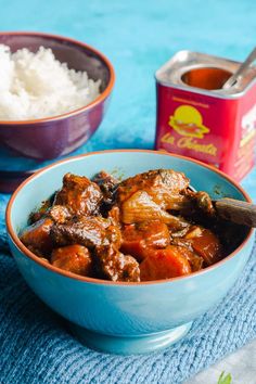 two bowls filled with meat and rice on top of a blue table cloth next to a can