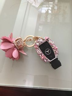 two keychains with flowers on them sitting on a glass counter top, one has a remote control attached to it