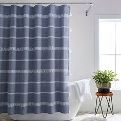 a bathroom with a blue shower curtain next to a potted plant